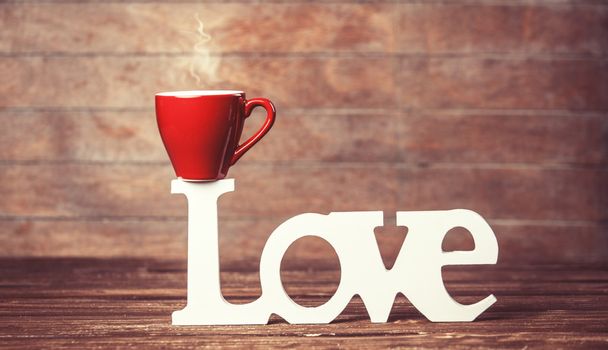 koffie of thee beker met woord liefde op woodent tafel. - Foto, afbeelding