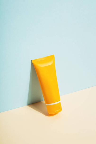 Orange tube of sunscreen on blue background. Sun Protection. Copy space - Foto, imagen