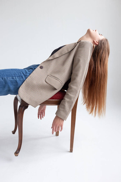 young caucasian woman with long hair lying on chair at studio with her chin up - Fotoğraf, Görsel