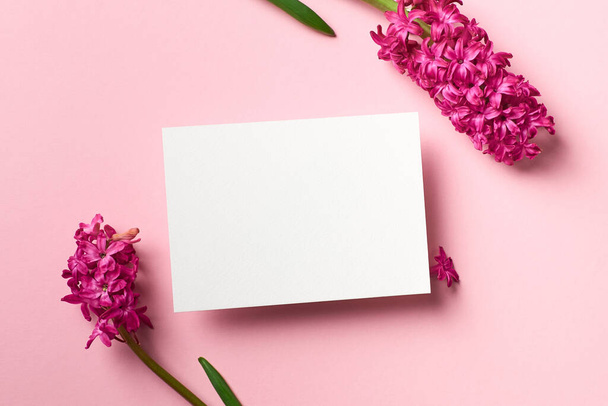 Greeting or invitation card mockup with spring hyacinth flowers on pink paper background, top view, copy space - Φωτογραφία, εικόνα