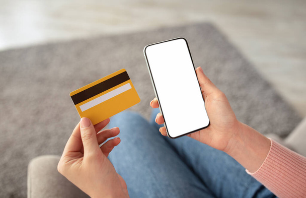 Łatwa zapłata. Kobieta trzyma smartfona z pustym ekranem i kartą kredytową do zakupu towarów w Internecie - Zdjęcie, obraz