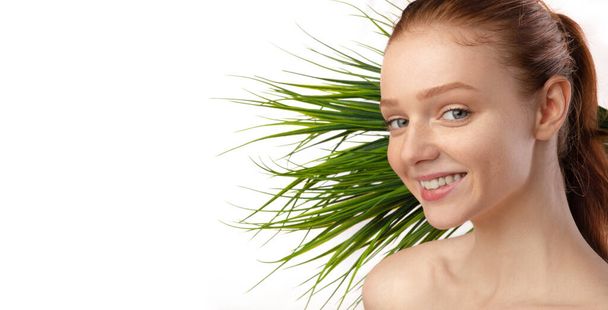 Jeune dame aux cheveux rouges heureux posant avec une plante verte, fond blanc - Photo, image