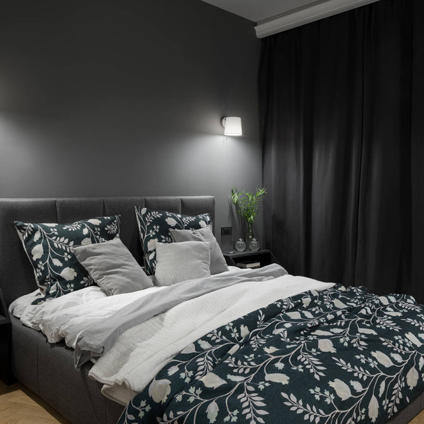 Big and comfortable bed in stylish and dark bedroom with gray walls, curtains and nice lighting - Foto, Imagen