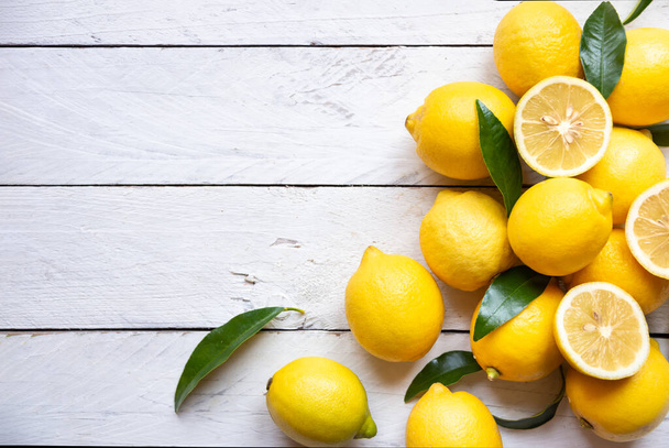 Свежие и спелые лимоны с листьями на белом дереве - Фото, изображение