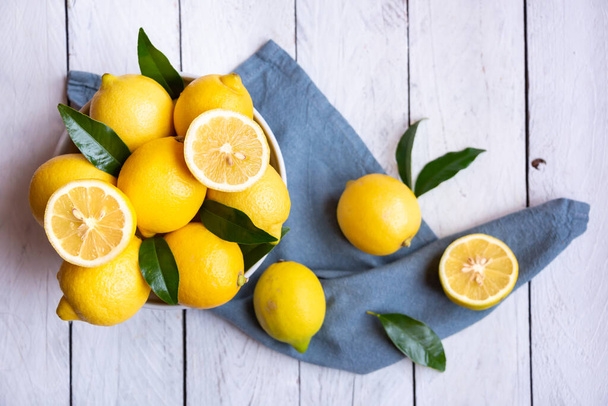 Fresh and ripe lemons with leaves on white wood - Foto, Imagen