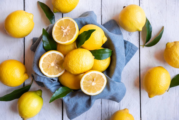 Fresh and ripe lemons with leaves on white wood - Zdjęcie, obraz