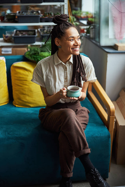Smiling florist having a coffee break at work - Foto, Imagen