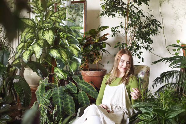 緑豊かな植物の花でいっぱいの部屋で椅子に座って穏やかな女性のラウンジ - 写真・画像