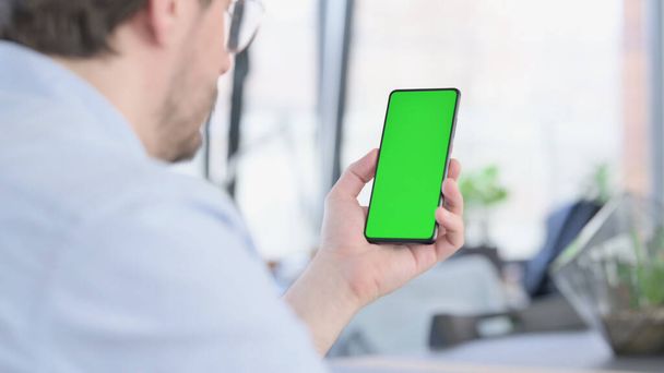 Man in glazen met smartphone met groen scherm  - Foto, afbeelding