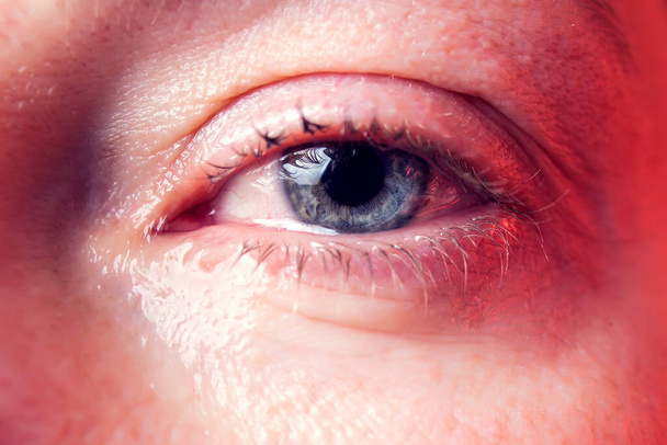Van dichtbij blauw oog van een vrouw met een traan. Mensen en emoties concept - Foto, afbeelding