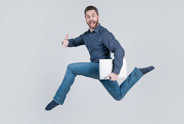 surprised energetic jumping man businessman running while working online on laptop hurry up for shopping show thumb up, success. - Foto, imagen
