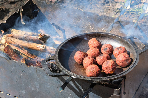 屋外の鍋でファラフェル料理.中東文化。自然のグリルのために用意された薪の火。キャンプでピクニック。自然の中でのグリルシーズンオープン. - 写真・画像
