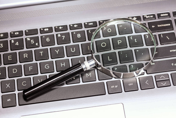 Vergrootglas op een modern laptop toetsenbord, loupe op een netbook, zoeken in bestanden, pc forensisch onderzoek. Web informatie zoeken, data zoekmachine eenvoudig concept, beter kijken, niemand - Foto, afbeelding