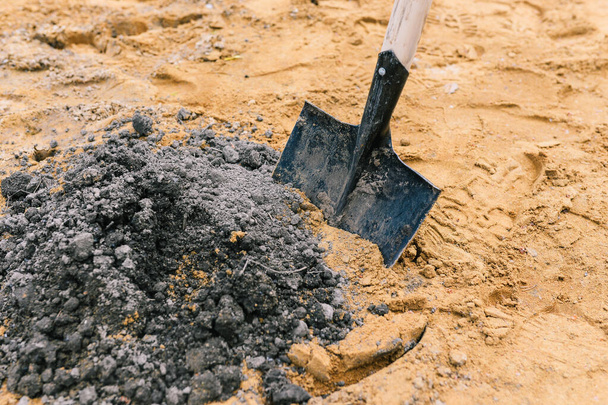 Černá lopata v písku. Nástroj pro sběr písku při stavebních pracích. Písek pro výstavbu a výsadbu - Fotografie, Obrázek