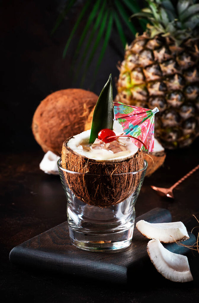 Pina Colada Summer Cocktail in chopped coconut with tropical fruits and copper bar tools, copy space - Foto, imagen