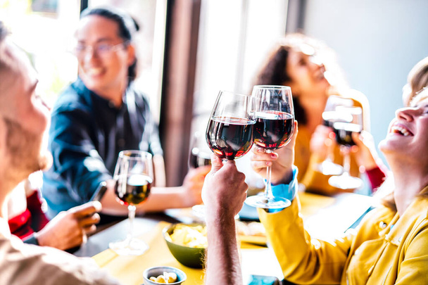 Mladí multietničtí lidé pití a opékání červeného vína na obědovém večírku - Happy opilý přátelé baví společně v restauraci vinařství bar - Fotografie, Obrázek