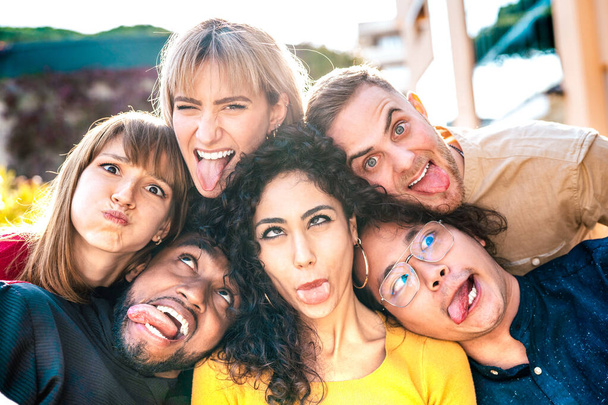Többnemzetiségű Y-generációs emberek, akik szelfit készítenek, boldog arccal kidugják a nyelvüket - Vicces életstílus és integrációs koncepció fajok közötti fiatal barátokkal, akik jól érzik magukat együtt - Fotó, kép