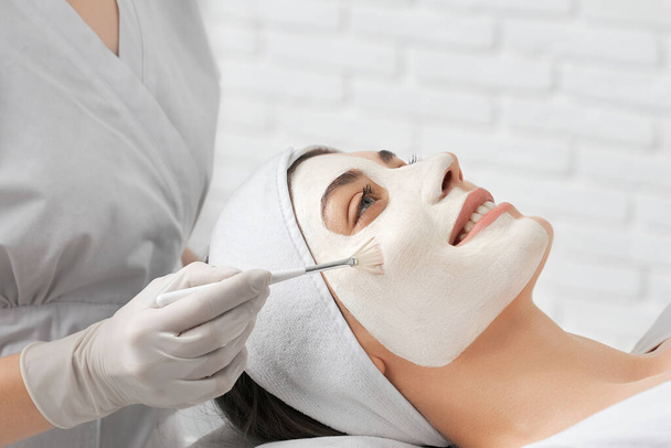 Smiling young woman doing procedure for face in beautician. - Foto, Imagem
