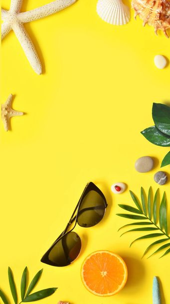 Summer background. Palm leaf, orange, starfish and seashell on yellow background. Travel. Copy space. - Photo, Image
