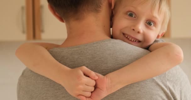 Surprised boy hugs his father. Son happily hugs his father by the shoulders. Blonde guy in his fathers arms - Imágenes, Vídeo
