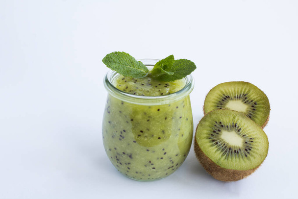 Kiwi smoothie or puree in the glass jar on the white background. Close-up. - Photo, Image