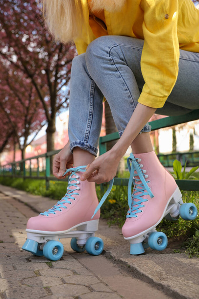 Young woman putting on roller skates outdoors, closeup - Foto, Imagen