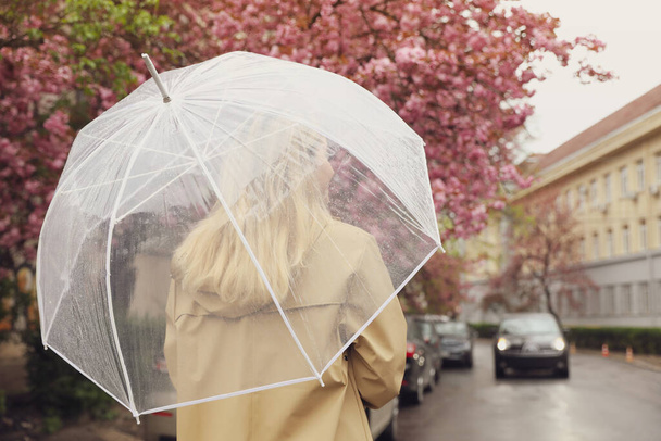 Young woman with umbrella on spring day, back view. Space for text - Foto, afbeelding