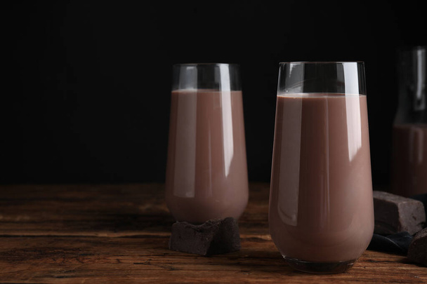 Delicious chocolate milk in glasses on wooden table - Фото, изображение