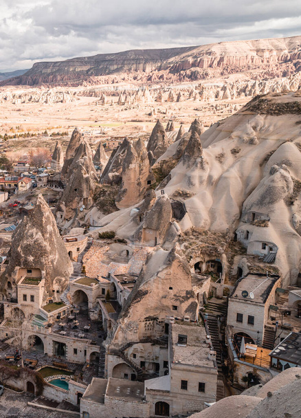 Goreme, Turcja - 20 marca 2021 - pionowy widok na centrum miasta Goreme w Kapadocji, Turcja z bajkowymi kominami, domami i unikalnymi formacjami skalnymi w humorzasty dzień - Zdjęcie, obraz