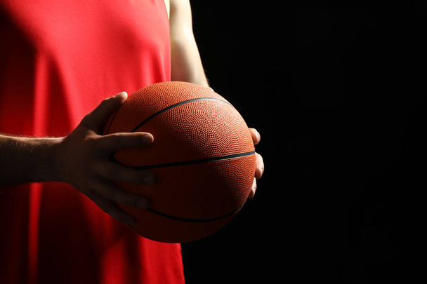 Basketball player with ball on black background, closeup. Space for text - Φωτογραφία, εικόνα
