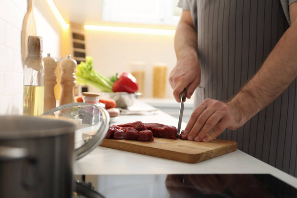 Man cutting meat to make bouillon in kitchen, closeup. Homemade recipe - Fotoğraf, Görsel