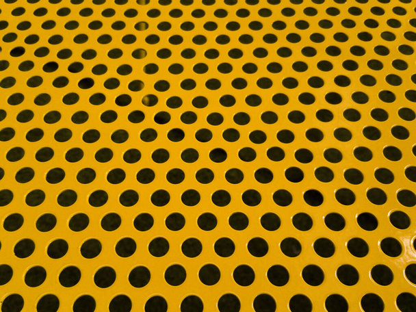 Agujeros redondos en placa metálica perforada amarilla
 - Foto, imagen