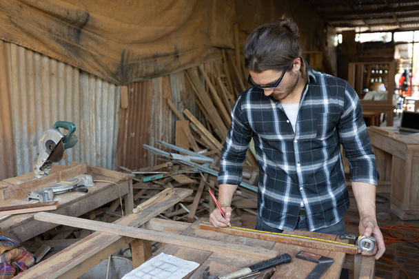 αρσενικό ξυλουργός μέτρησης ξύλου με μολύβι και ταινία μέτρο στο εργαστήριο - Φωτογραφία, εικόνα