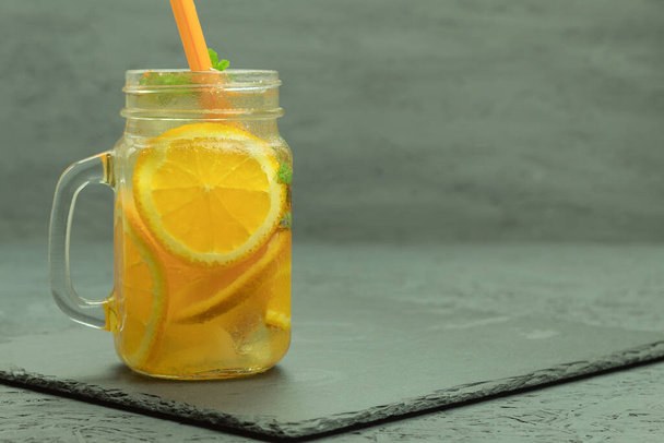 Fajna lemoniada z pomarańczy i kostek lodu. Krople wody. Odświeżający napój owocowy na rustykalnym drewnianym tle. Tło z miejscem na tekst - Zdjęcie, obraz