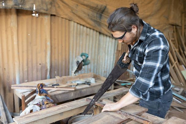 male carpenter using iron cutter blade for cutting wood in workshop - Foto, Imagem