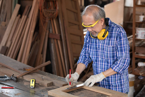 falegname uomo anziano misura legno con righello in officina - Foto, immagini