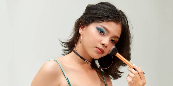 portrét ženy používající make-up štětec nanášení suché kosmetické tonální základ na její obličej - Fotografie, Obrázek