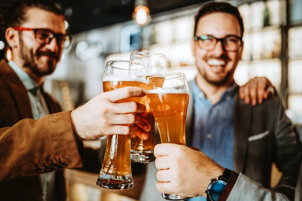 Happy business people drink beer after work in pub. Businessmen enjoy a beer. - Foto, Imagen
