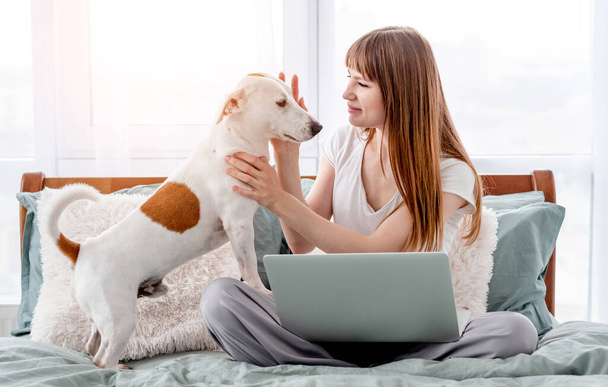 Girl with dog and laptop in the bed - Fotoğraf, Görsel
