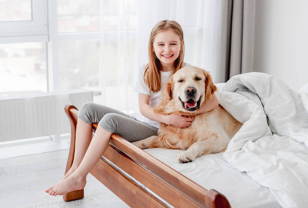Girl with golden retriever dog in the bed - Foto, Imagen