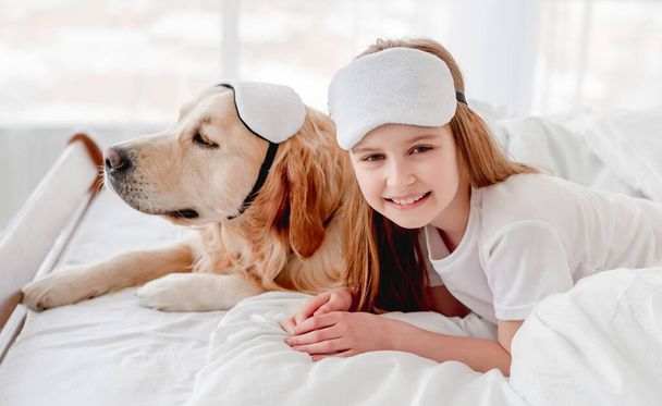 Girl with golden retriever dog in the bed - Foto, afbeelding