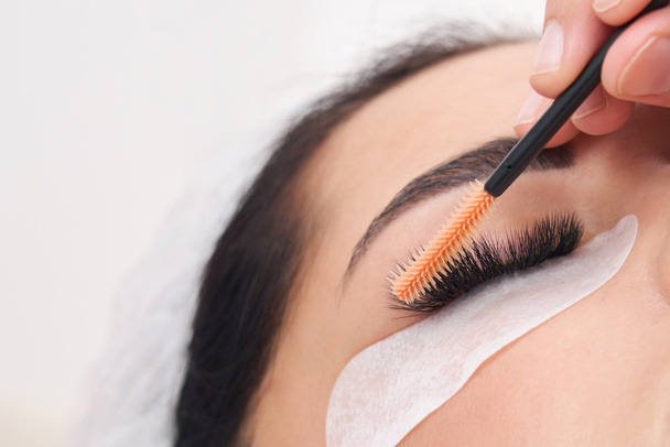 Kosmetologe macht Wimpernverlängerung und Korrektur mit Pinsel - Foto, Bild