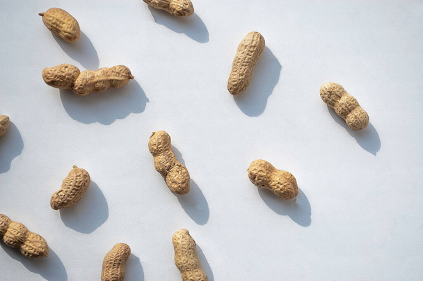 unpeeled peanuts on a white background - Фото, изображение