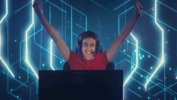 Professional eSports Gamer Playing in Computer Video Games, Happily and Cheerfully Celebrates Victory and Success with Raised Hands. Online Cyber Championship Tournament. Portrait View - 写真・画像