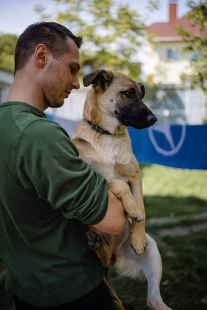 Jovem voluntário acariciando cão triste no abrigo de animais - Foto, Imagem