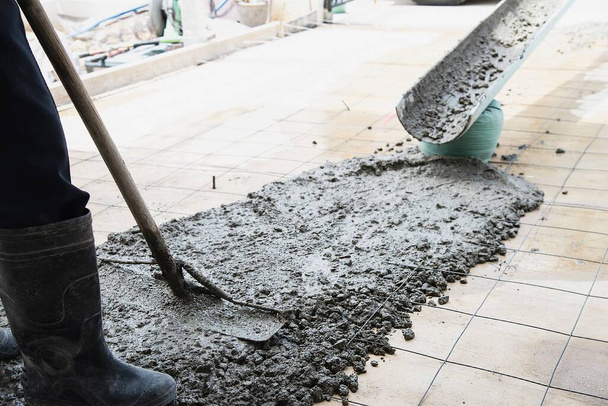 Workman doing floor concrete pouring job in construction site - Foto, afbeelding