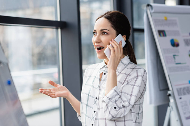 Izgatott üzletasszony beszél okostelefonon az irodában  - Fotó, kép