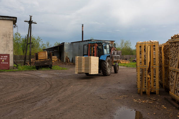 Traktorin kuormat levyt, puutavaraa lopputuotteen varastosta kuorma-auton konttiin - Valokuva, kuva
