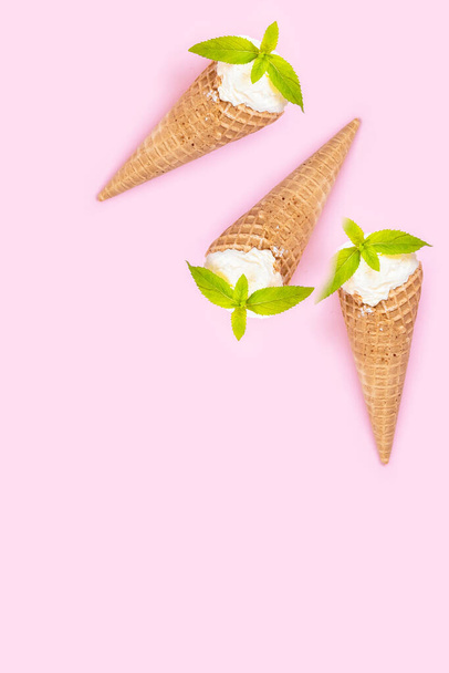 Mint vanilla ice cream with in a waffle cone with mint leaves on pink background. - 写真・画像
