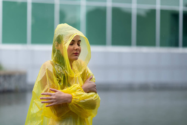 Πορτρέτο των γυναικών που φορούν κίτρινο αδιάβροχο ενώ βρέχει την εποχή των βροχών - Φωτογραφία, εικόνα
